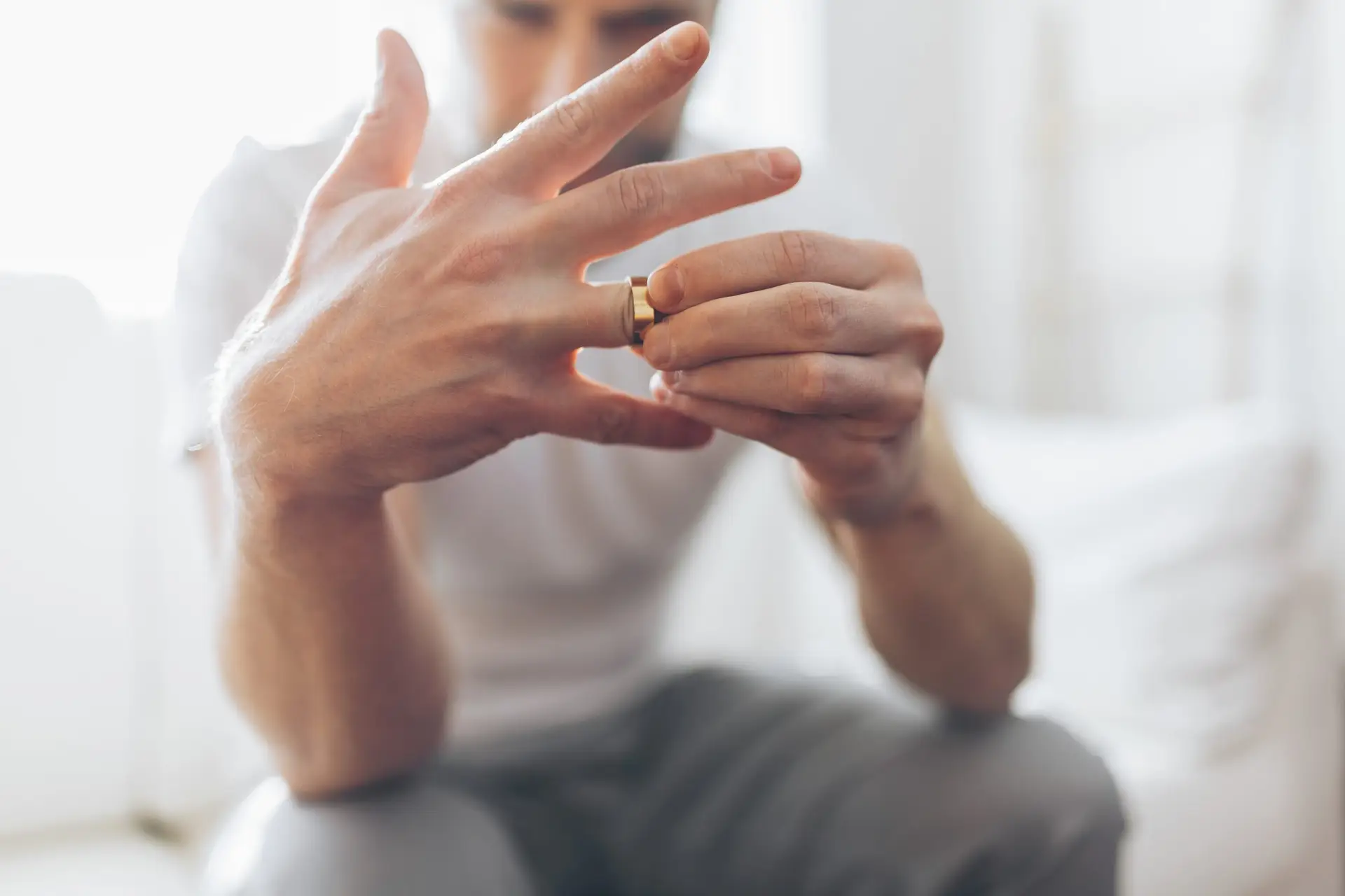 Heartbroken man at home holding a wedding ring