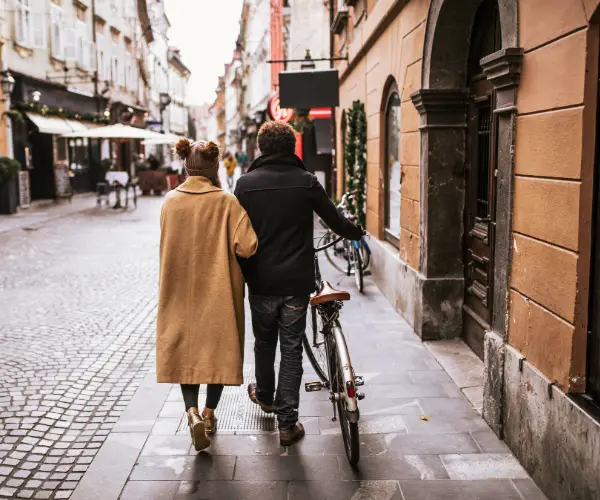A couple walking together with a bicycle.